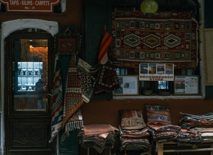 A charming shop with colorful Turkish carpets and rugs displayed outside, with a warm ambiance and intricate textile patterns.