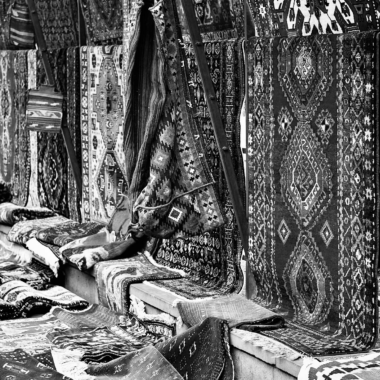 A collection of ornate handmade carpets on display at a traditional market stall.