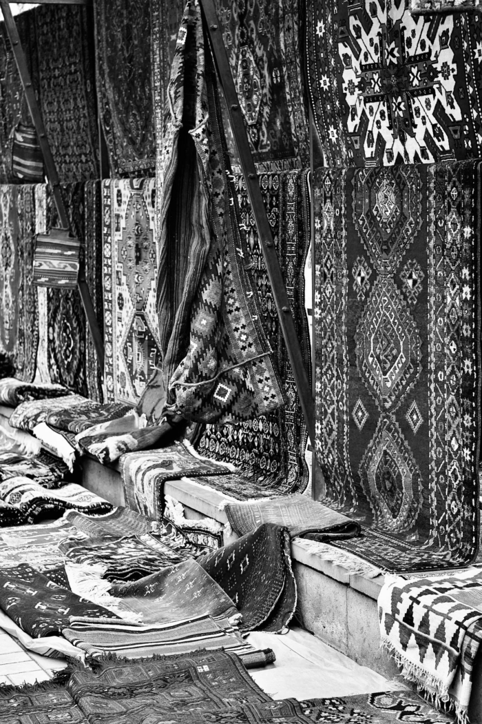 A collection of ornate handmade carpets on display at a traditional market stall.