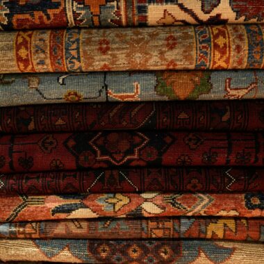 A detailed view of stacked handmade Persian rugs showcasing intricate patterns and rich colors.