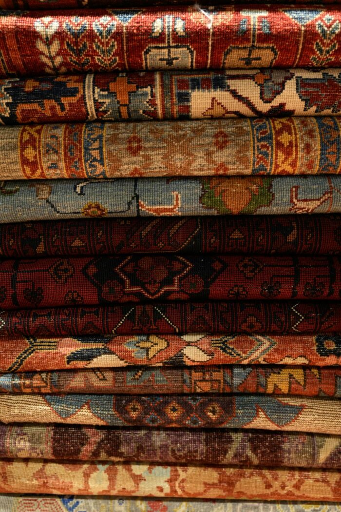 A detailed view of stacked handmade Persian rugs showcasing intricate patterns and rich colors.