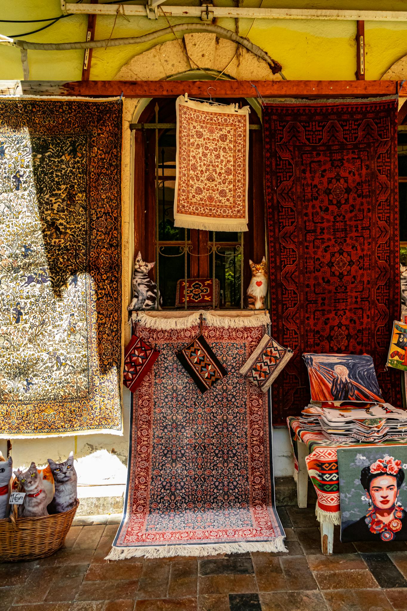 A vibrant display of rugs and figurines at a market stall, showcasing intricate designs and patterns.