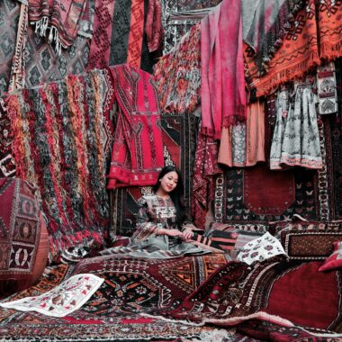 A vibrant display of traditional Turkish rugs and textiles in an indoor market.