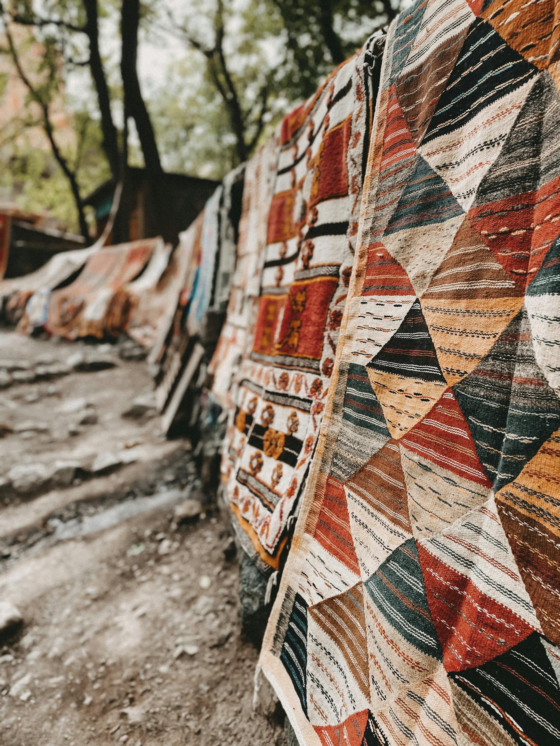 Close-up of traditional colorful rugs displayed outdoors in Ain Soltane, Algeria.