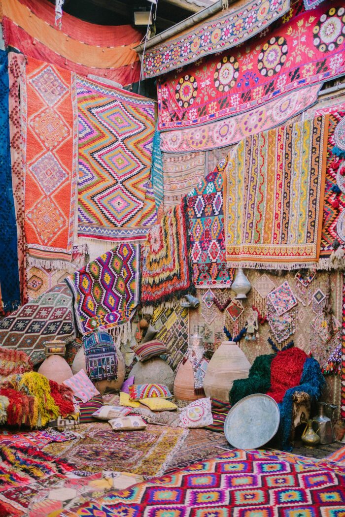 Colorful handmade carpets and pottery on display in a traditional market setting.