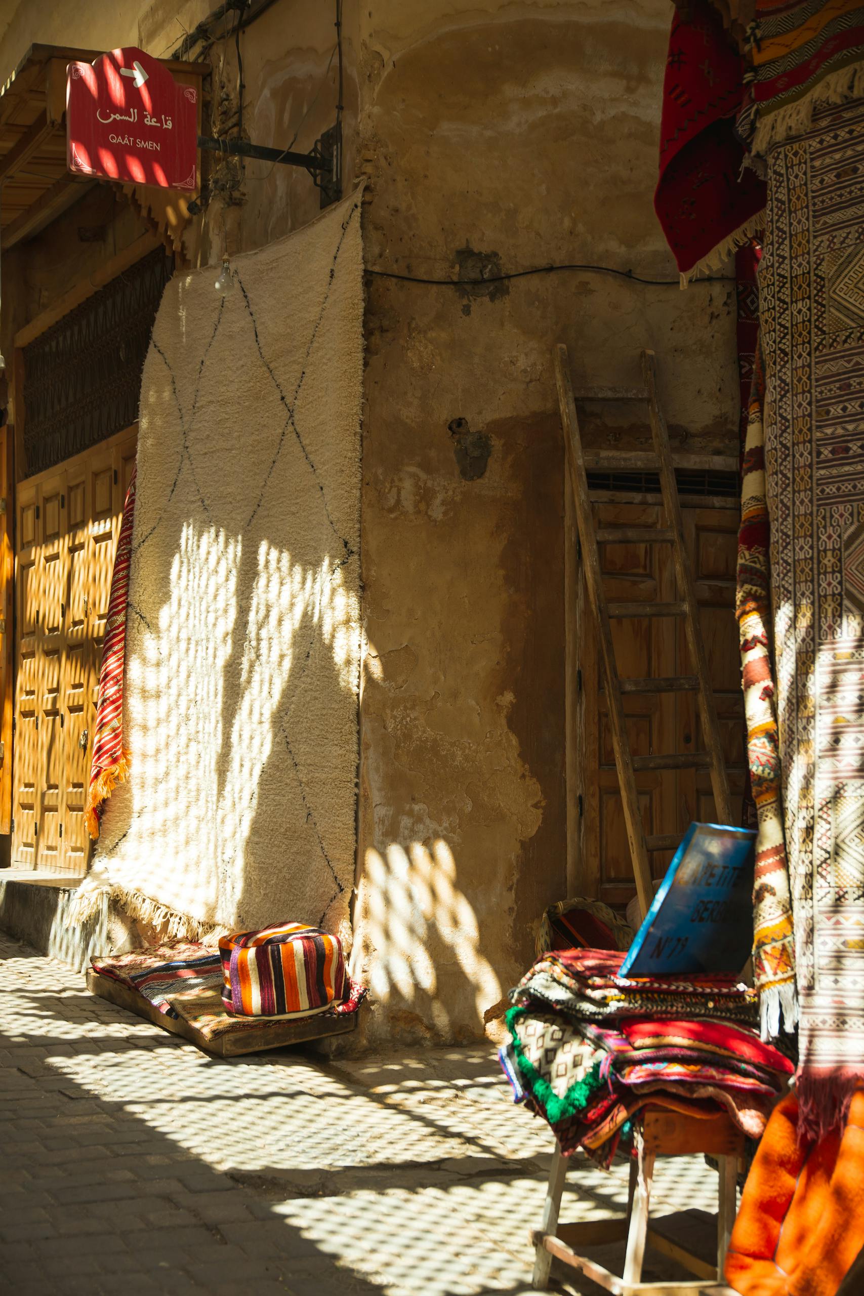 Sunlit Moroccan street with colorful textiles and rustic charm in Fes.