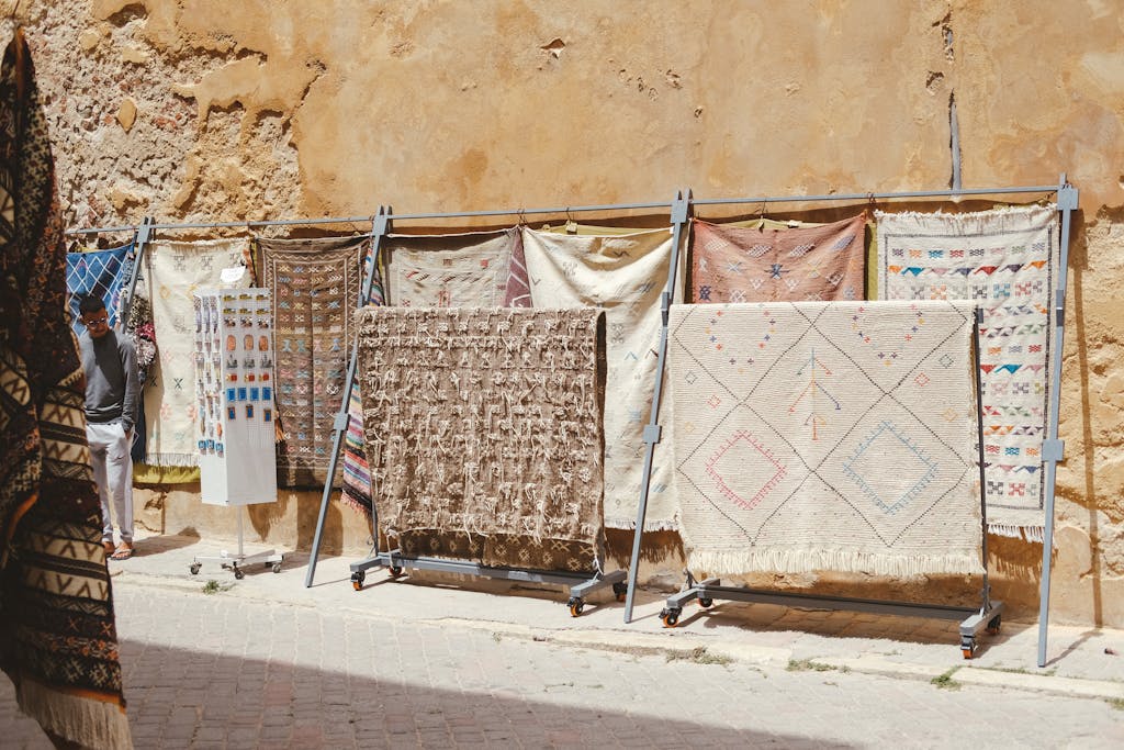 Traditional Moroccan rugs on display against an ancient wall in El Jadida, Morocco.