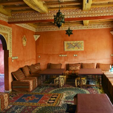 Vibrant Moroccan interior with traditional decor, patterns, and cozy seating in a sunlit living room.