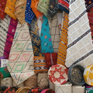 Vibrant Moroccan rugs and cushions on display, showcasing intricate designs and craftsmanship.
