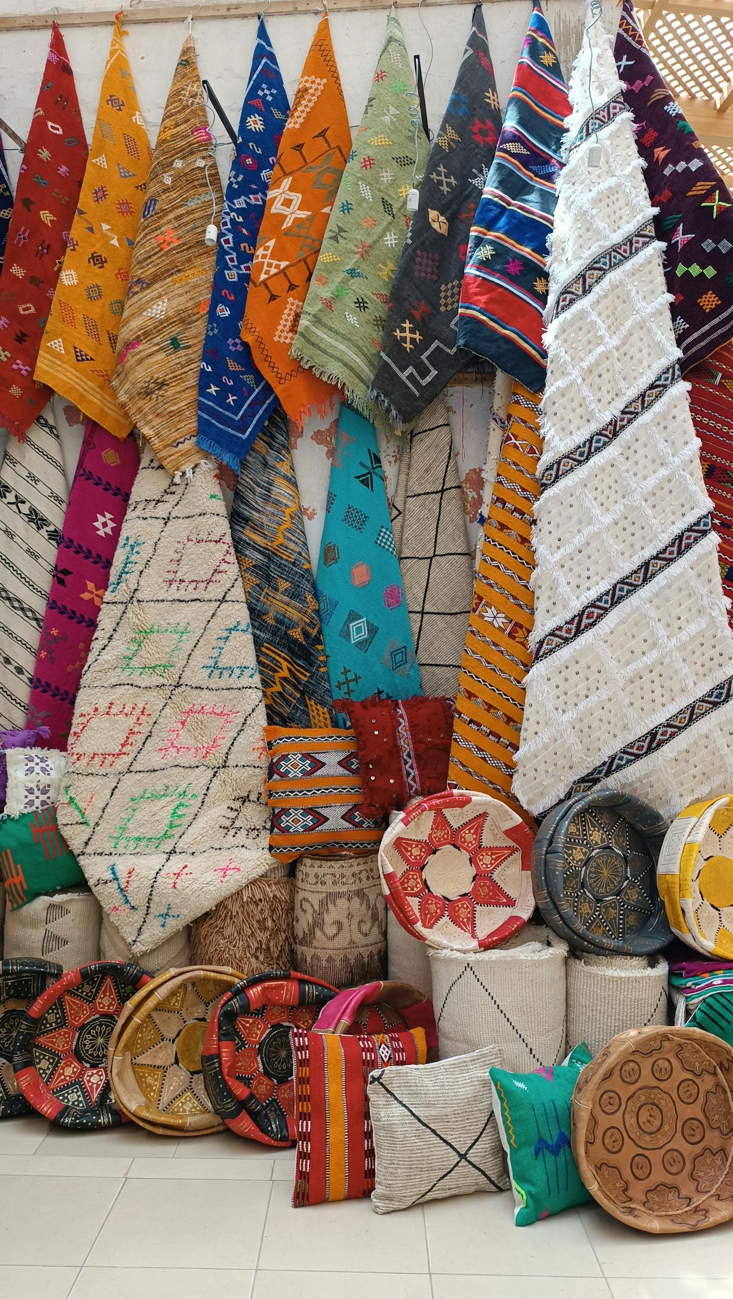 Vibrant Moroccan rugs and cushions on display, showcasing intricate designs and craftsmanship.